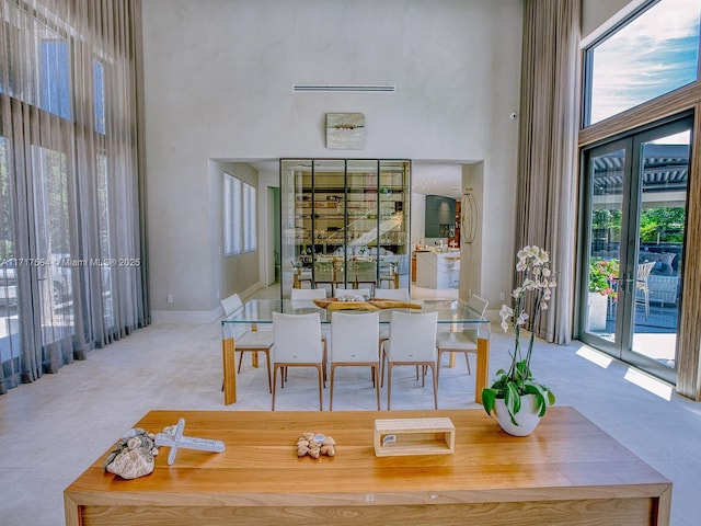 tiled dining room featuring a towering ceiling and french doors