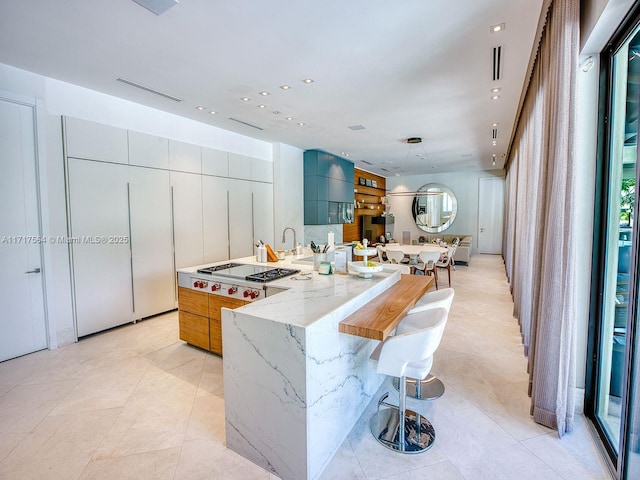 kitchen featuring a kitchen bar, light stone counters, light tile patterned flooring, and a large island