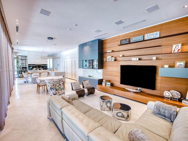 living room with light tile patterned flooring and wooden walls