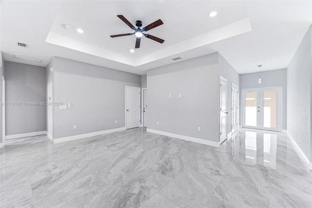 spare room featuring a raised ceiling, ceiling fan, and french doors