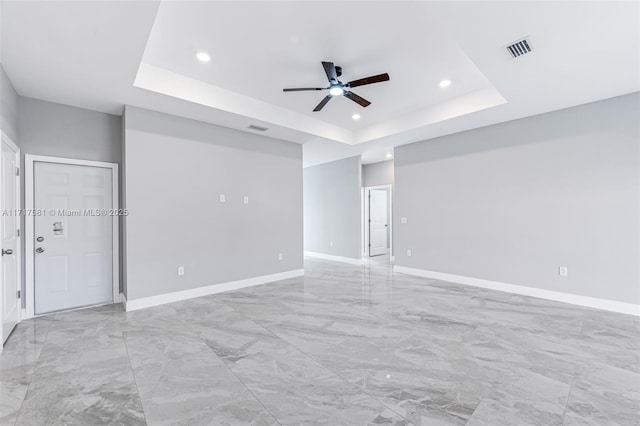 empty room featuring a raised ceiling and ceiling fan