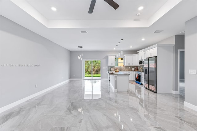 kitchen featuring white cabinets, hanging light fixtures, ceiling fan, appliances with stainless steel finishes, and a kitchen island