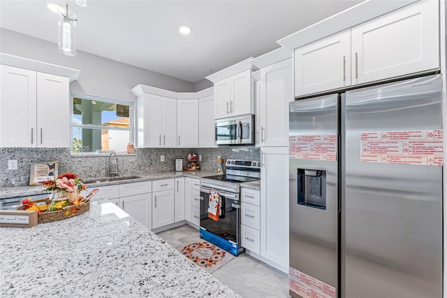 kitchen with white cabinetry, sink, tasteful backsplash, light stone counters, and appliances with stainless steel finishes