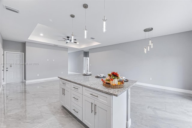 kitchen featuring light stone countertops, a raised ceiling, ceiling fan, decorative light fixtures, and white cabinetry