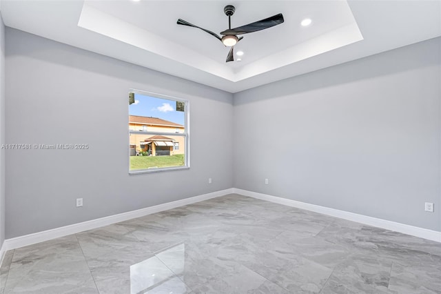 spare room featuring a tray ceiling and ceiling fan