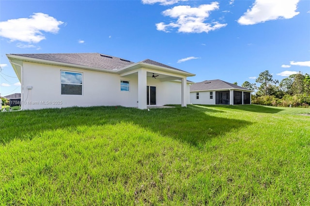 back of property with a sunroom, ceiling fan, and a yard