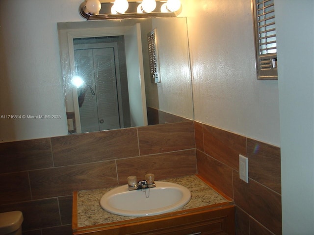 bathroom featuring vanity and tile walls