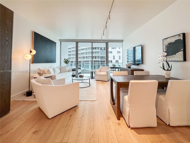 living room featuring a wall of windows, track lighting, and light hardwood / wood-style floors