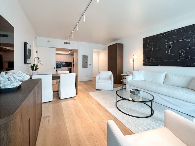 living room featuring rail lighting, electric panel, and light hardwood / wood-style floors