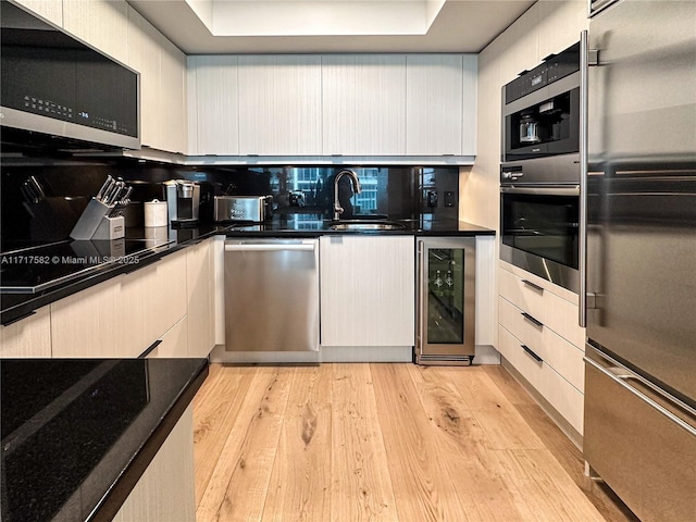 kitchen with sink, backsplash, beverage cooler, light hardwood / wood-style floors, and stainless steel appliances