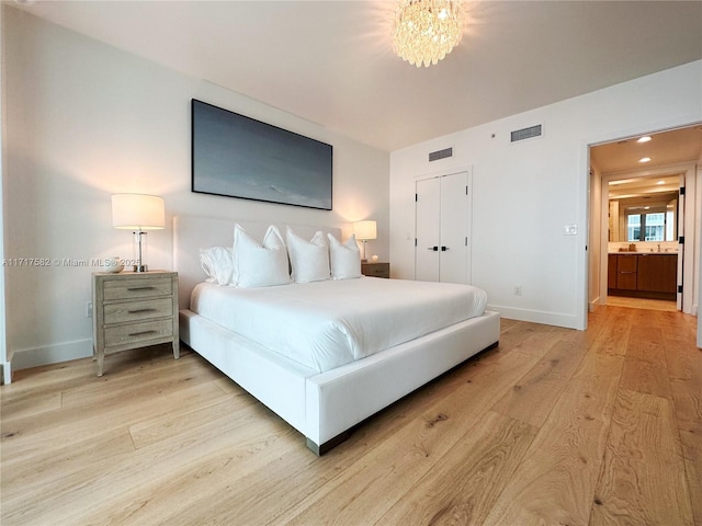 bedroom with a chandelier, light hardwood / wood-style floors, and a closet