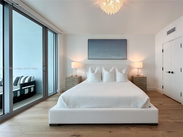 bedroom with a notable chandelier, access to outside, and light wood-type flooring