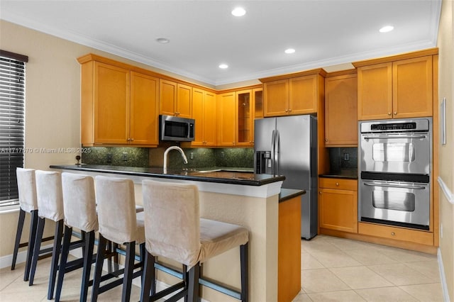 kitchen featuring crown molding, a breakfast bar, light tile patterned floors, and appliances with stainless steel finishes