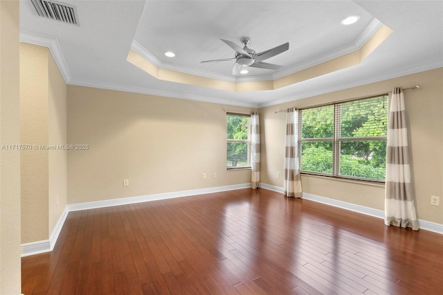 empty room featuring dark hardwood / wood-style floors, a raised ceiling, ceiling fan, and ornamental molding