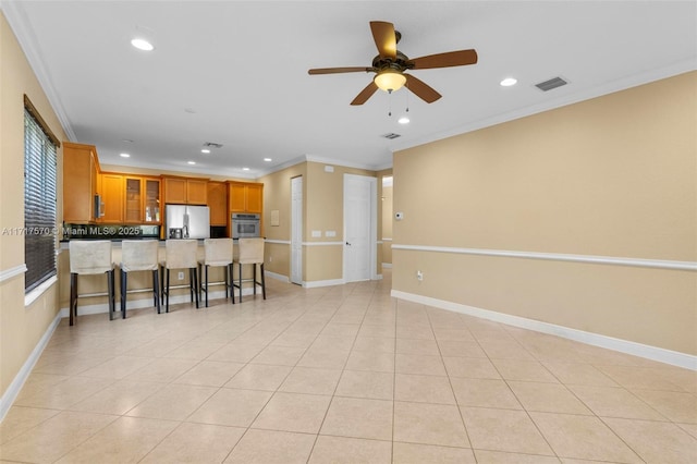 kitchen featuring appliances with stainless steel finishes, a kitchen breakfast bar, ceiling fan, crown molding, and light tile patterned floors