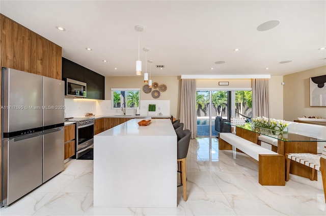 kitchen featuring pendant lighting, a kitchen island, sink, and stainless steel appliances