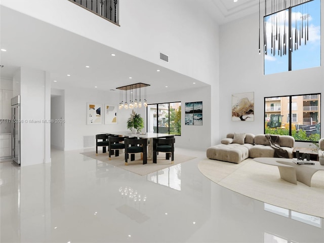 tiled living room featuring a towering ceiling and a notable chandelier