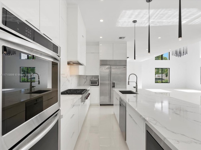 kitchen featuring white cabinetry, sink, light stone counters, pendant lighting, and appliances with stainless steel finishes