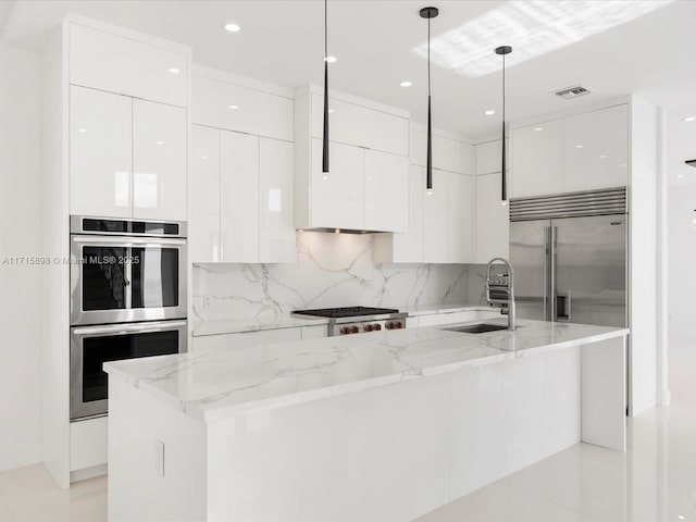 kitchen with light stone countertops, stainless steel appliances, sink, pendant lighting, and white cabinets