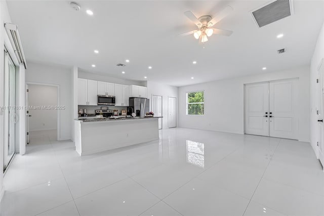 kitchen featuring white cabinets, ceiling fan, light tile patterned floors, appliances with stainless steel finishes, and stone countertops