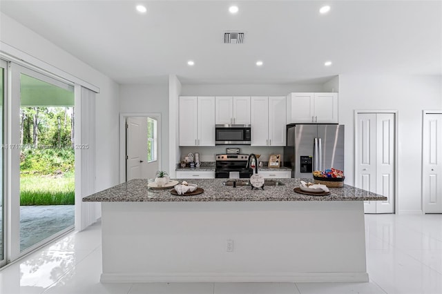 kitchen with stone counters, an island with sink, and appliances with stainless steel finishes