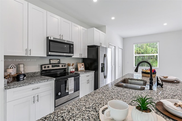 kitchen with light stone counters, white cabinetry, sink, and appliances with stainless steel finishes