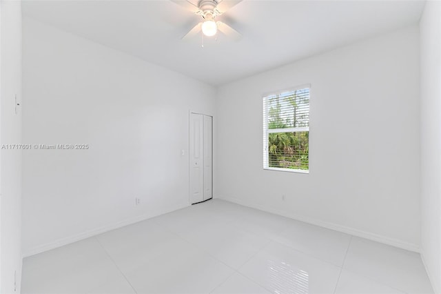 tiled spare room featuring ceiling fan