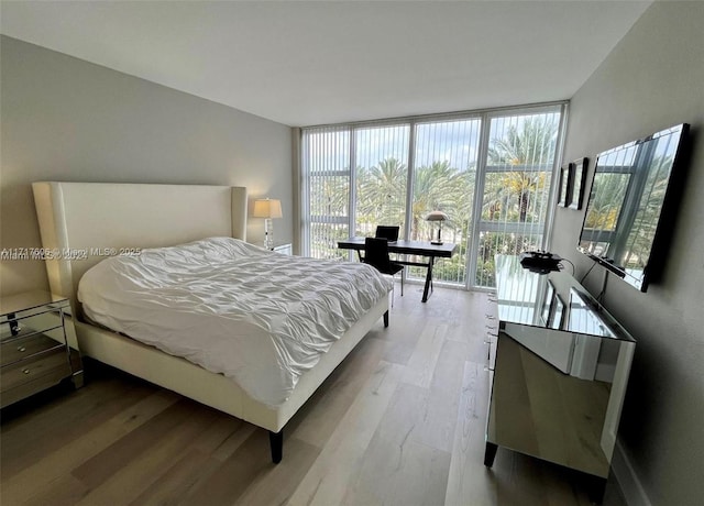 bedroom with light wood-type flooring and a wall of windows