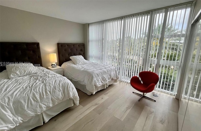 bedroom featuring access to exterior, light hardwood / wood-style floors, and multiple windows