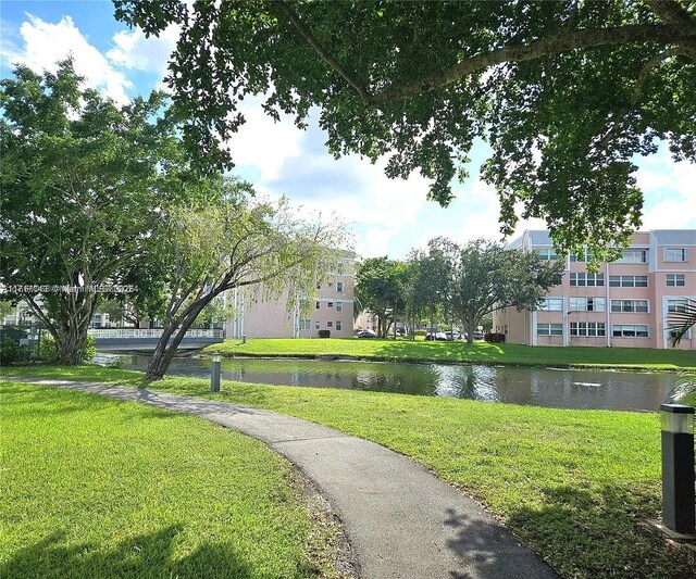 surrounding community with a water view and a yard