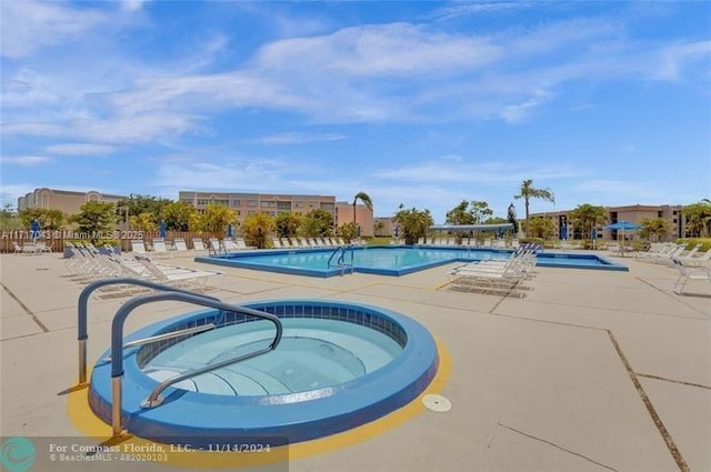 view of pool with a patio area and a hot tub