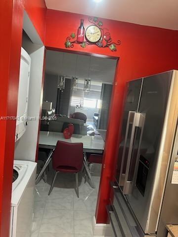 kitchen featuring stainless steel fridge and stacked washing maching and dryer