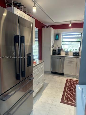 kitchen with white cabinets, appliances with stainless steel finishes, and rail lighting