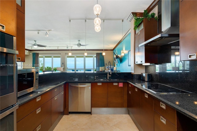 kitchen featuring ceiling fan, sink, wall chimney exhaust hood, stainless steel appliances, and pendant lighting