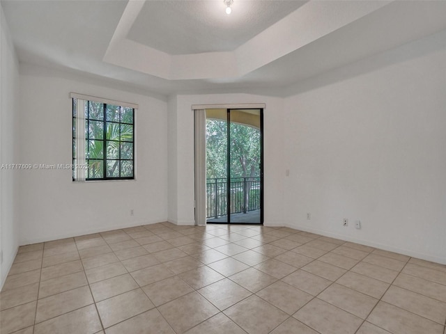 unfurnished room featuring a raised ceiling and light tile patterned floors