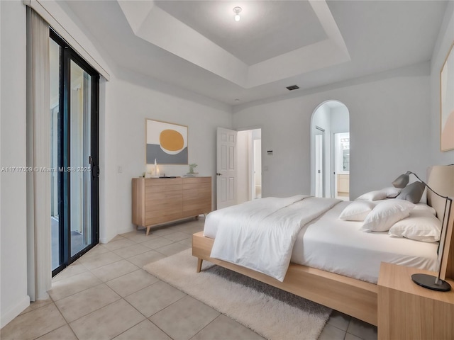 tiled bedroom featuring a tray ceiling and access to exterior