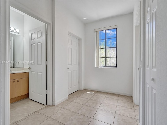 unfurnished bedroom with ensuite bathroom and light tile patterned floors