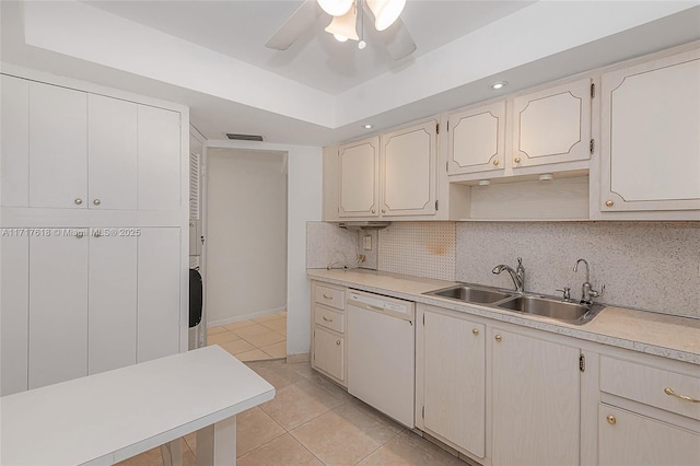 kitchen with white dishwasher, a raised ceiling, sink, decorative backsplash, and light tile patterned floors