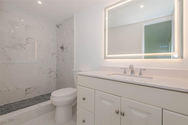 bathroom with a tile shower, vanity, and toilet