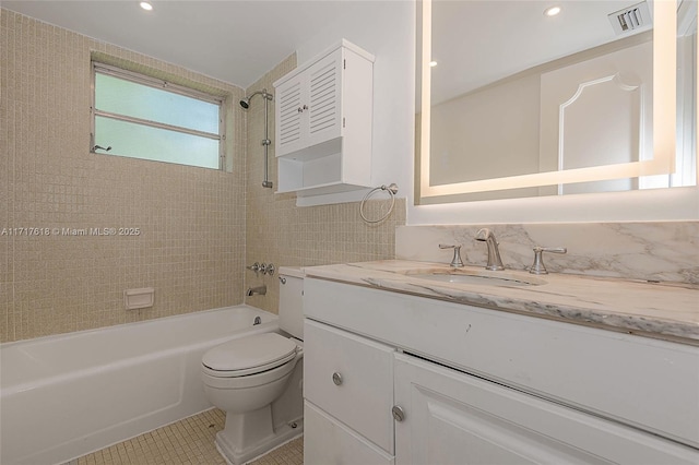 full bathroom featuring vanity, tile patterned floors, tiled shower / bath combo, toilet, and tile walls