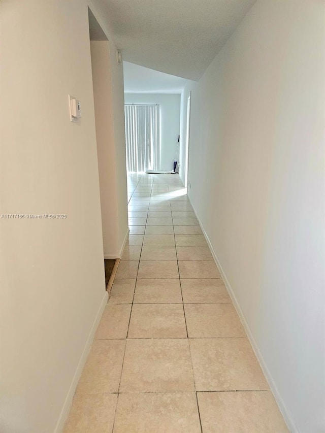 hallway featuring light tile patterned floors and vaulted ceiling