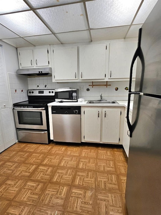 kitchen featuring a paneled ceiling, backsplash, white cabinets, sink, and stainless steel appliances