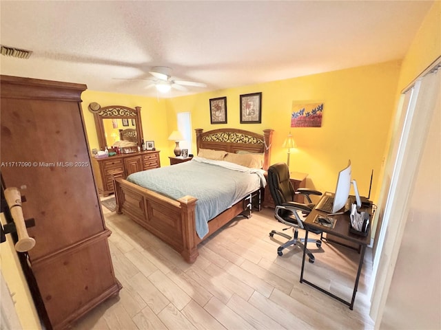 bedroom with a textured ceiling, light hardwood / wood-style flooring, and ceiling fan