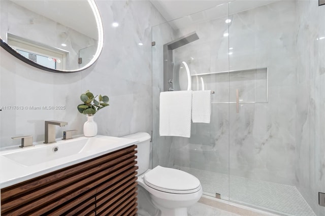 bathroom featuring vanity, toilet, a shower with door, and tile walls