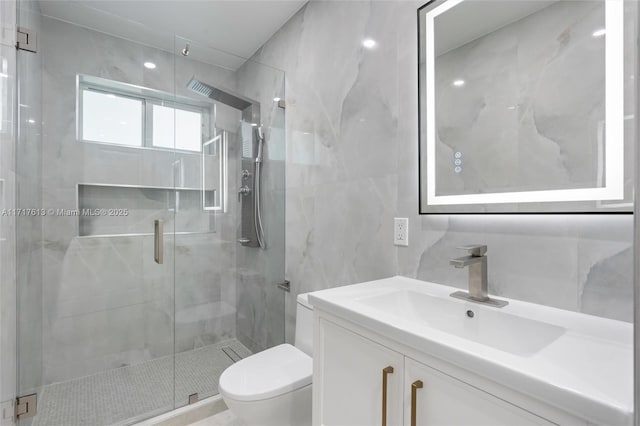 bathroom featuring vanity, toilet, walk in shower, and tile walls