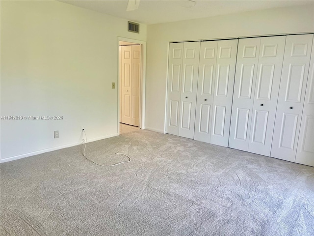 unfurnished bedroom with ceiling fan, light colored carpet, and a closet