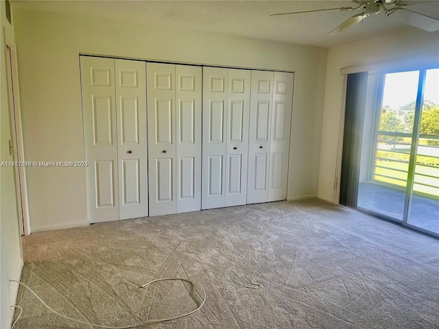 unfurnished bedroom with carpet, access to exterior, a closet, and ceiling fan