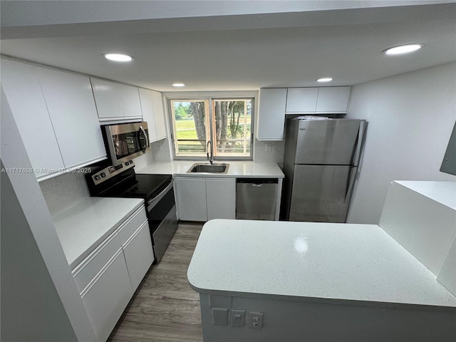 kitchen with dark wood-type flooring, sink, appliances with stainless steel finishes, tasteful backsplash, and white cabinetry