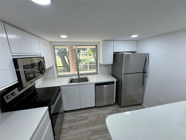 kitchen with backsplash, stainless steel appliances, sink, light hardwood / wood-style flooring, and white cabinets