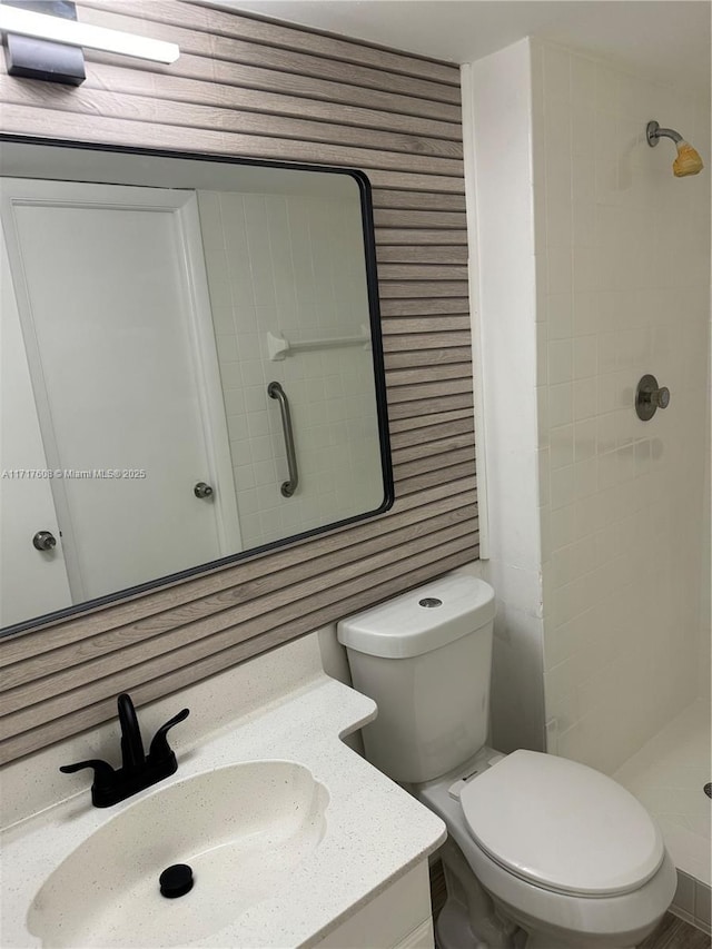 bathroom with a shower, vanity, wood walls, and toilet